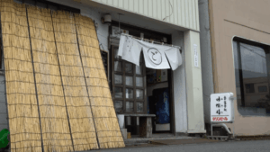 味愉嬉食堂の暖簾がかかった入口と、店前に立てられた立て看板。飲食店の外観