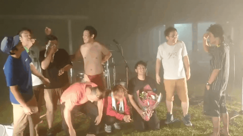 ライブ終了後、メンバーとスタッフがカメラの前に集合。ボーカルは花束をもらって中央に座っている。