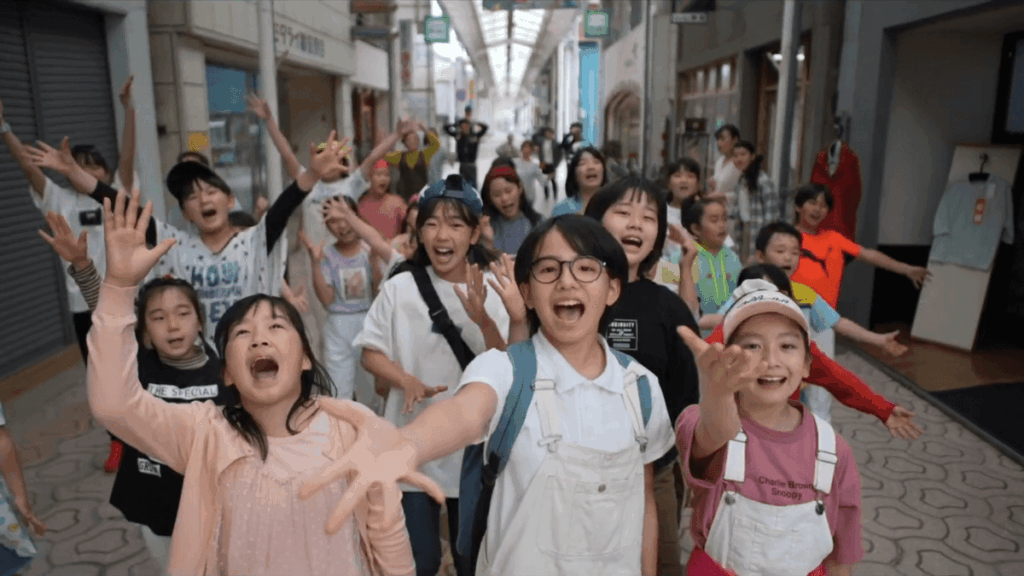 僕とムーサの物語の出演者が歌いながら佐伯市の商店街を練り歩く様子